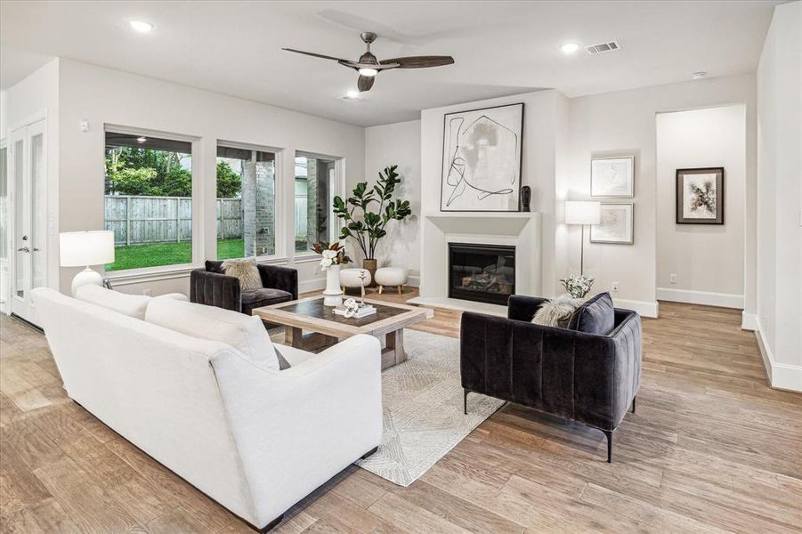 Experience unparalleled comfort in this expansive living room, where warm wood floors and designer touches create a welcoming ambiance. Whether you're enjoying quiet moments alone or entertaining guests, this versatile space is perfectly suited for both. The hallway to the right leads to the primary retreat.