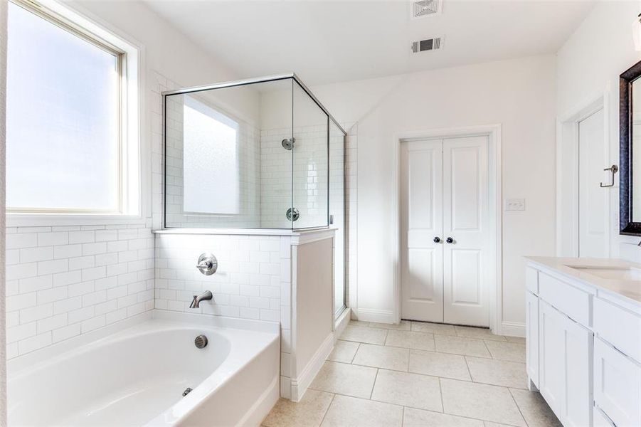 Bathroom with tile patterned flooring, vanity, and separate shower and tub