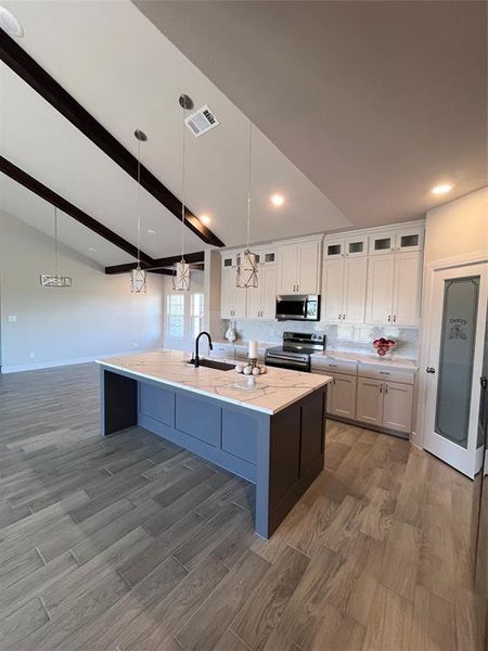 Kitchen with pendant lighting, white cabinetry, sink, and range