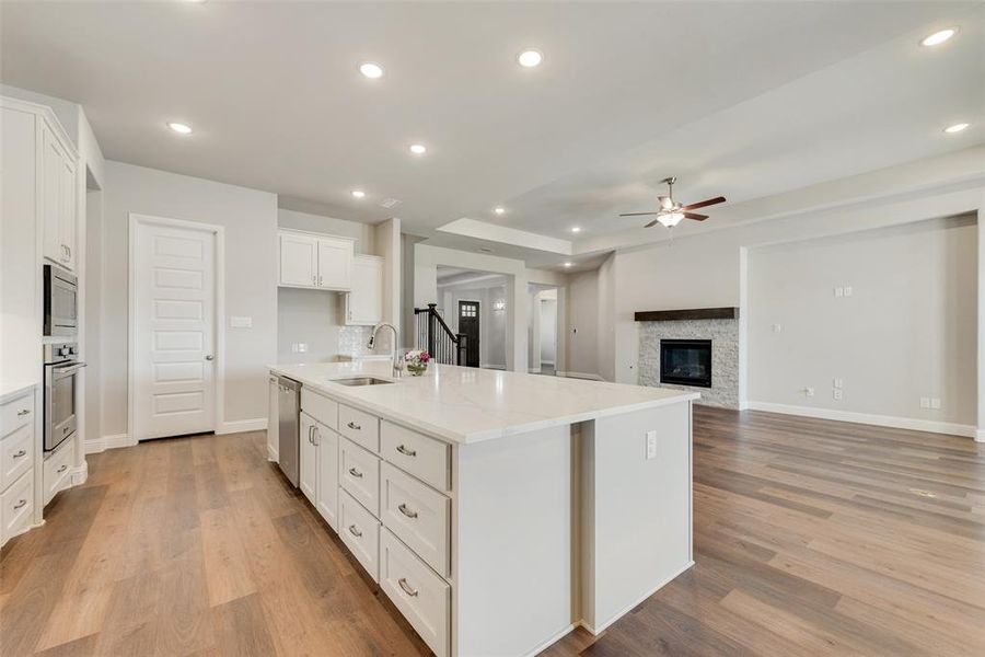 Kitchen with sink, a center island with sink, white cabinetry, stainless steel appliances, and light hardwood / wood-style floors