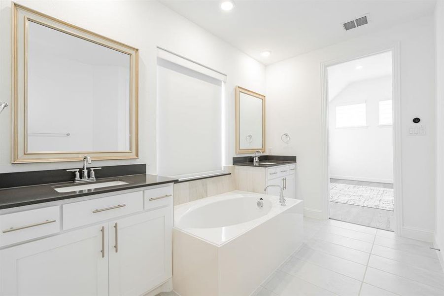 Bathroom with a bath, dual sinks, tile flooring, and oversized vanity
