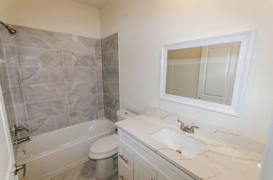 Full bathroom featuring toilet, tiled shower / bath combo, and vanity