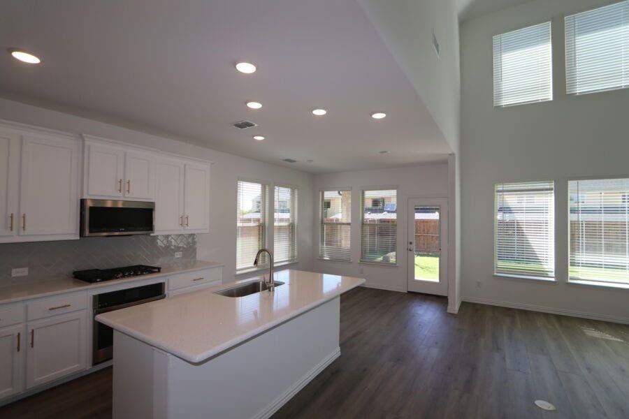 Kitchen with stainless steel appliances, white cabinets, sink, and a center island with sink