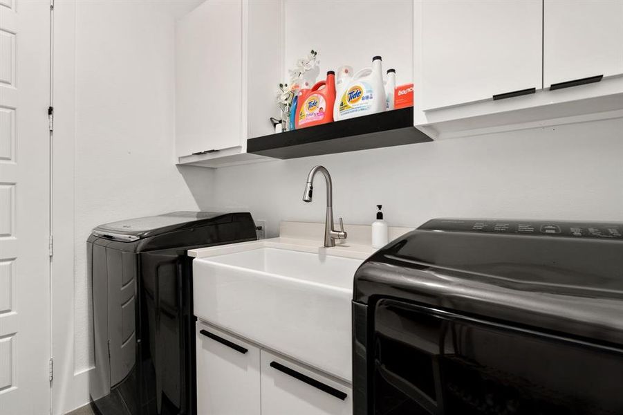Laundry room featuring sink, washer and clothes dryer, and cabinets