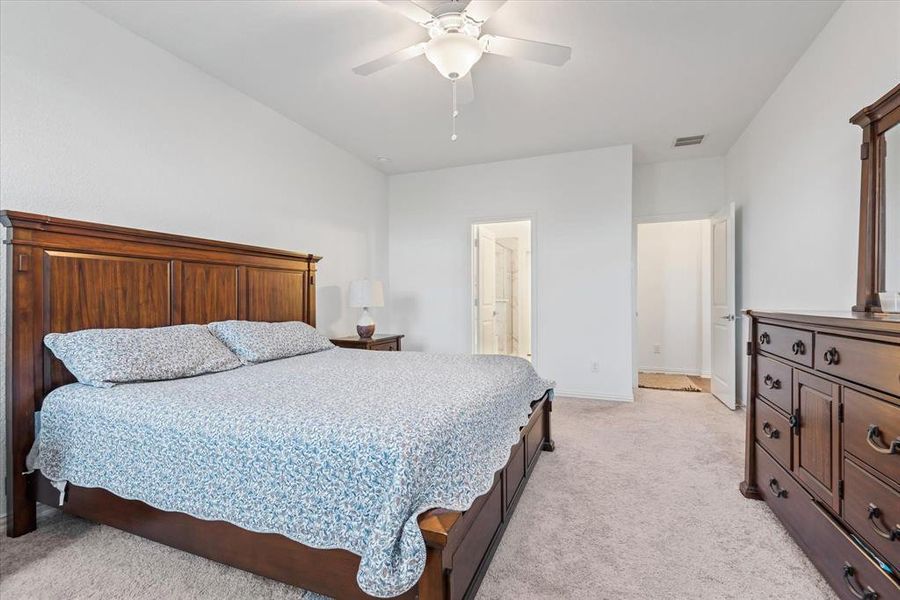 Carpeted bedroom featuring connected bathroom and ceiling fan