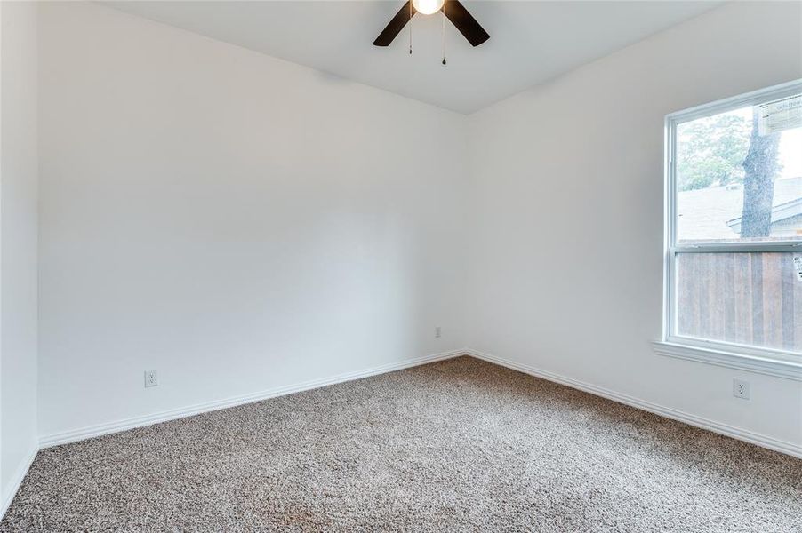 Carpeted empty room featuring ceiling fan