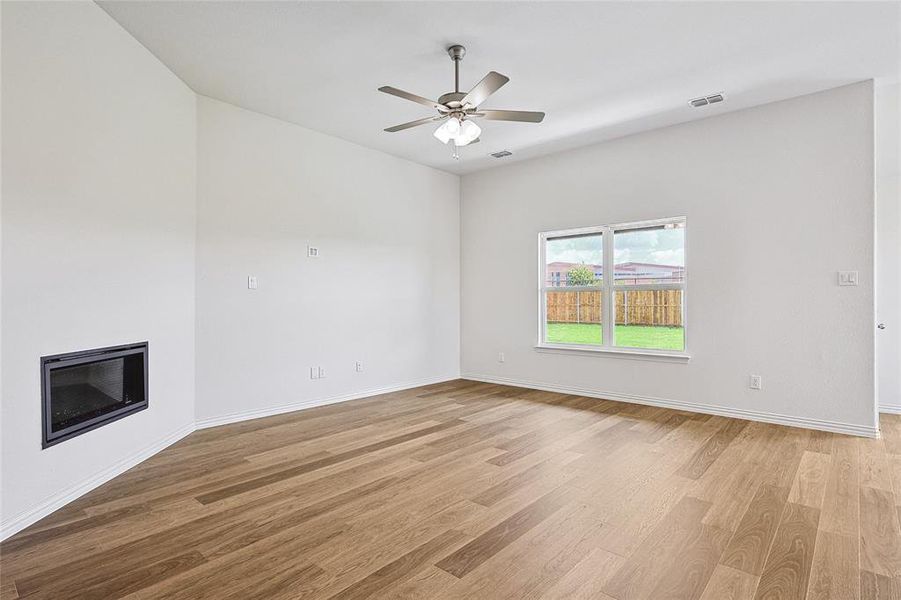 Unfurnished living room with ceiling fan, heating unit, and light hardwood / wood-style flooring