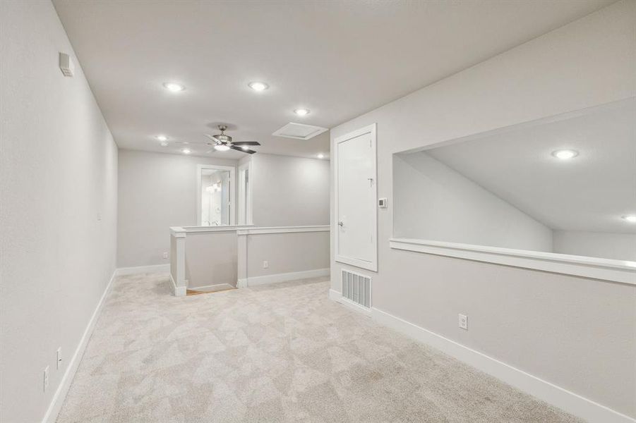 Basement with ceiling fan and light colored carpet