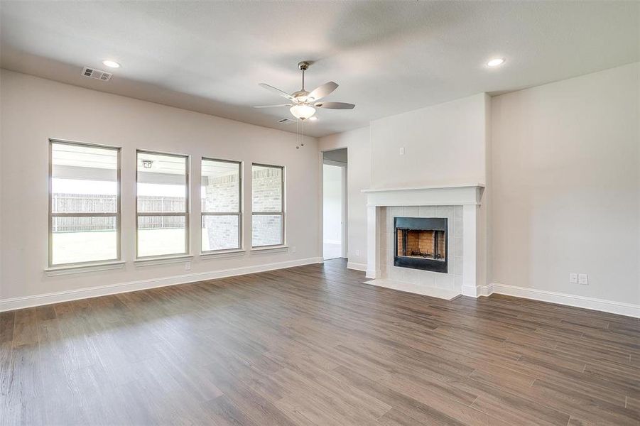 Unfurnished living room with dark wood-type flooring, ceiling fan, and a fireplace