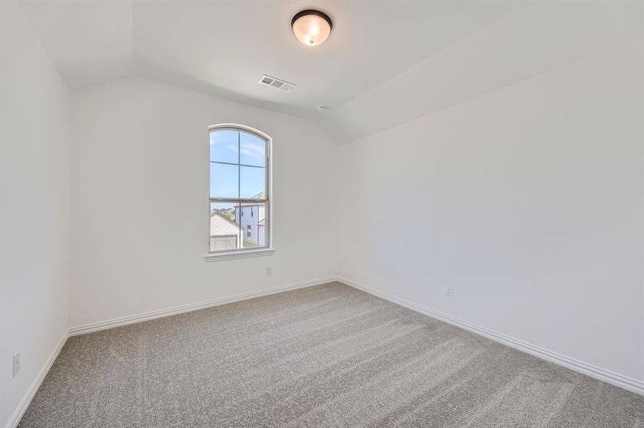 Carpeted empty room with vaulted ceiling