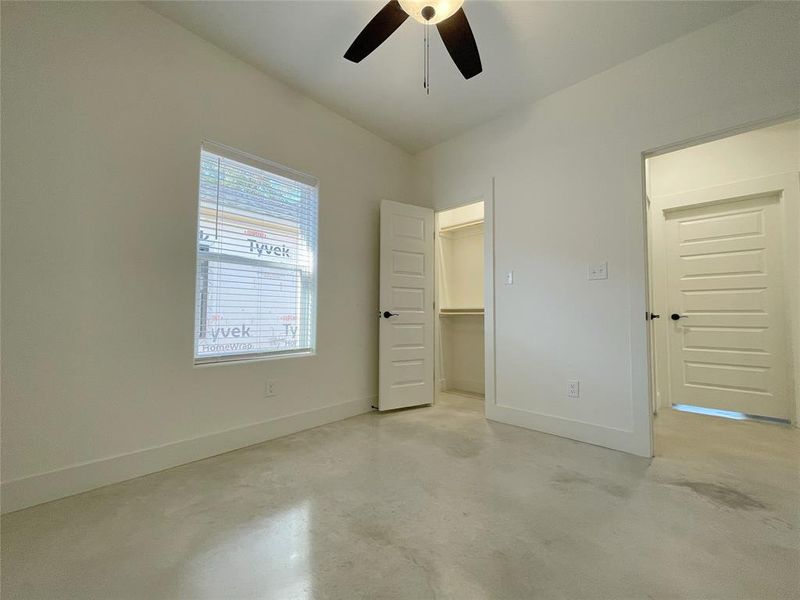 Unfurnished bedroom with a spacious closet, ceiling fan, and a closet