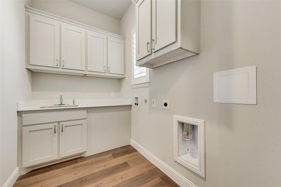 Laundry area featuring washer hookup, sink, cabinets, light wood-type flooring, sink and tons of storage