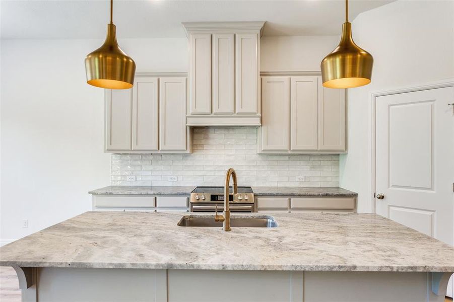 Kitchen featuring a center island with sink, decorative light fixtures, and backsplash