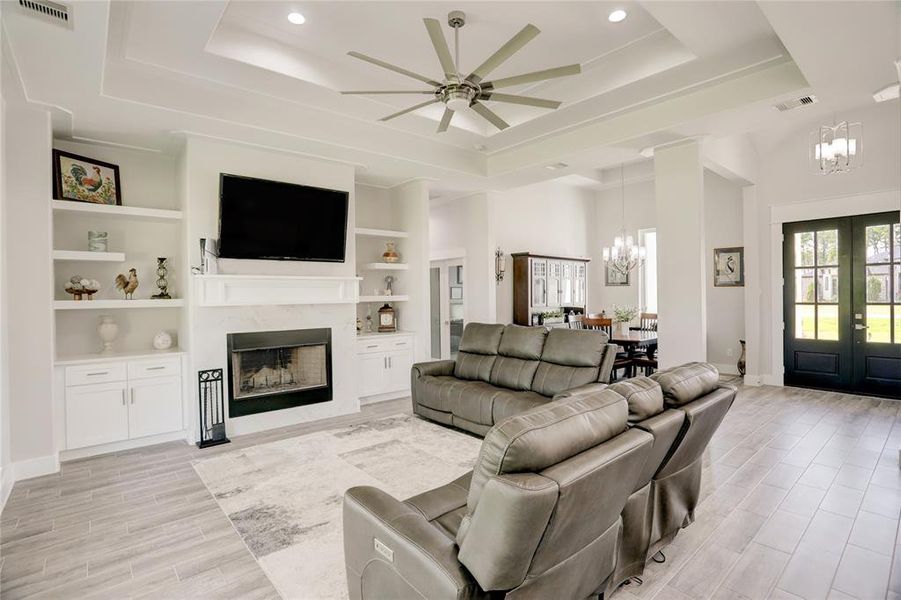 UNWIND IN THIS SPACIOUS LIVING ROOM THAT EXUDES CONTEMPORARY ELEGANCE, FEATURING A COZY FIREPLACE, CUSTOM BUILT-IN SHELVING, AND HIGH CEILINGS THAT ENHANCE THE OPEN AND AIRY FEEL.