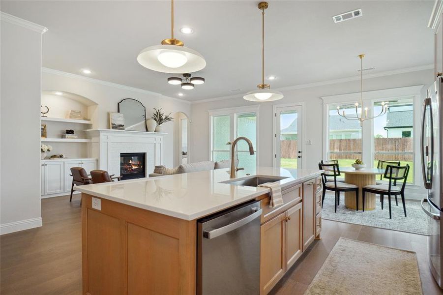 Kitchen featuring an island with sink, stainless steel appliances, light hardwood / wood-style floors, sink, and ornamental molding
