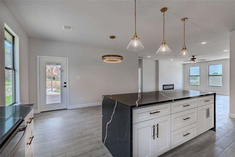 Kitchen featuring decorative light fixtures, ceiling fan, hardwood / wood-style flooring, a center island, and white cabinets