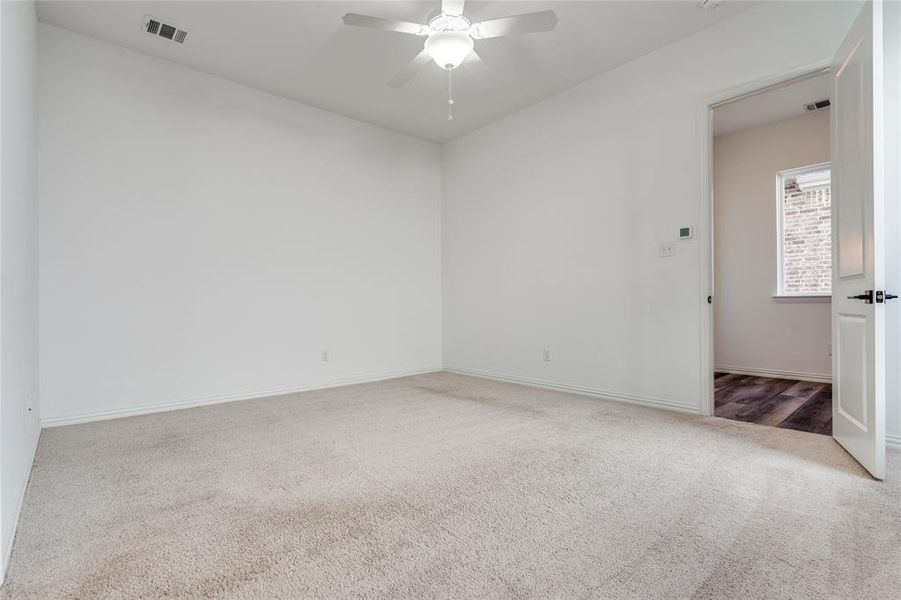 Carpeted empty room featuring ceiling fan