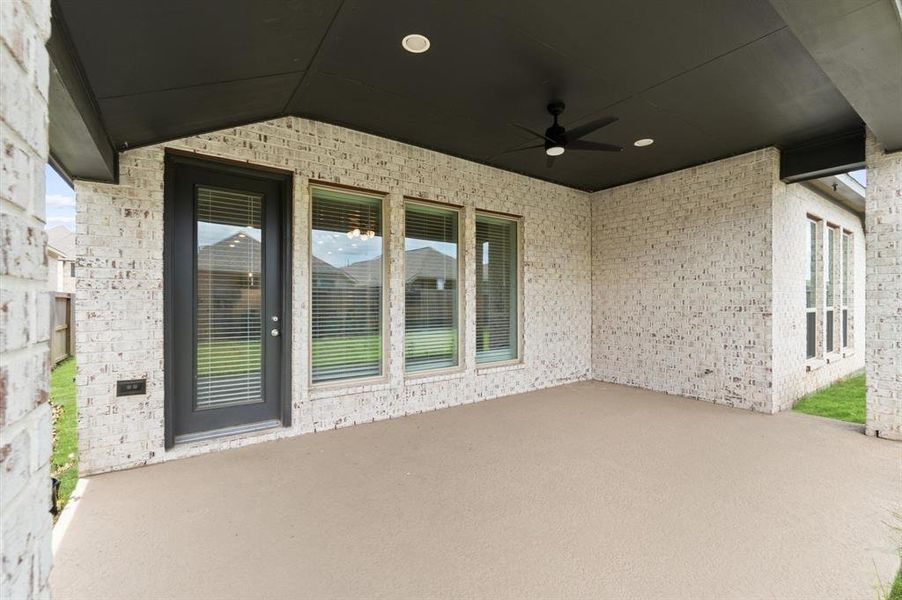 The spacious covered patio features a ceiling fan and provides a comfortable outdoor living space. It's ideal for relaxing, entertaining, or enjoying the garden.