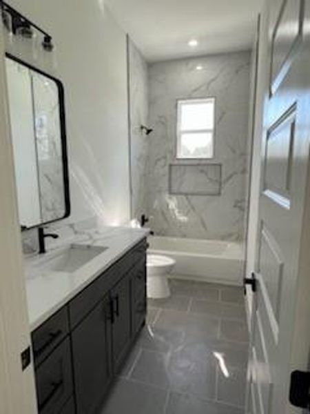 Full bathroom with vanity, tiled shower / bath combo, and toilet