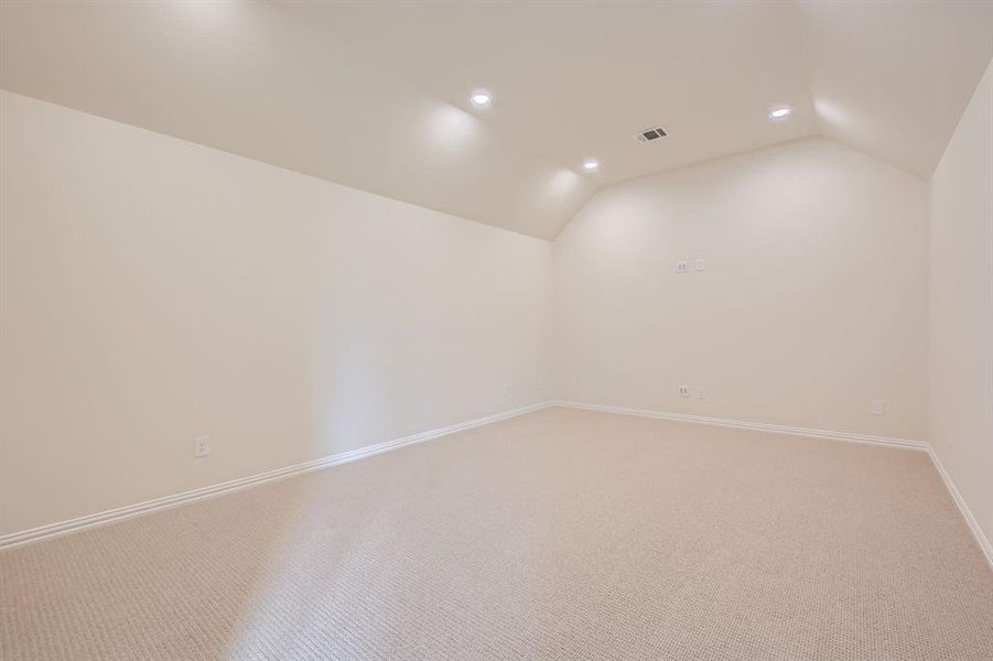 Carpeted spare room with lofted ceiling