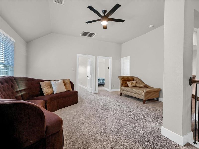 Living room with ceiling fan, carpet flooring, and lofted ceiling