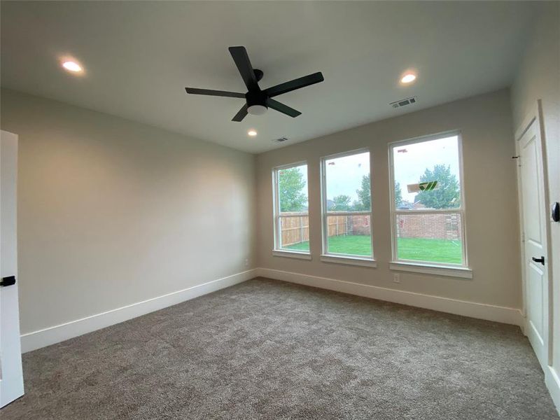 Carpeted empty room featuring ceiling fan