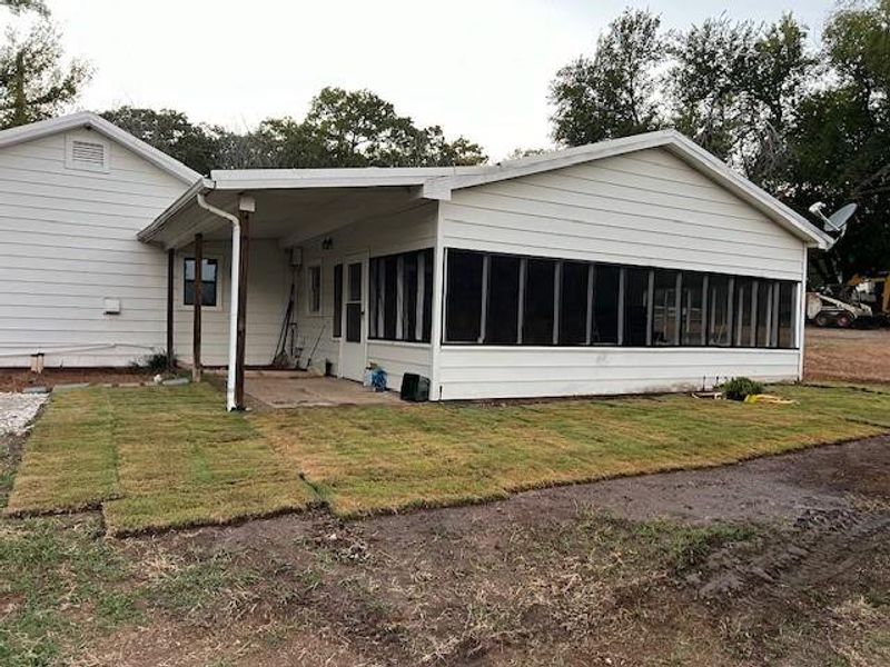 Rear view of property featuring a yard and a sunroom