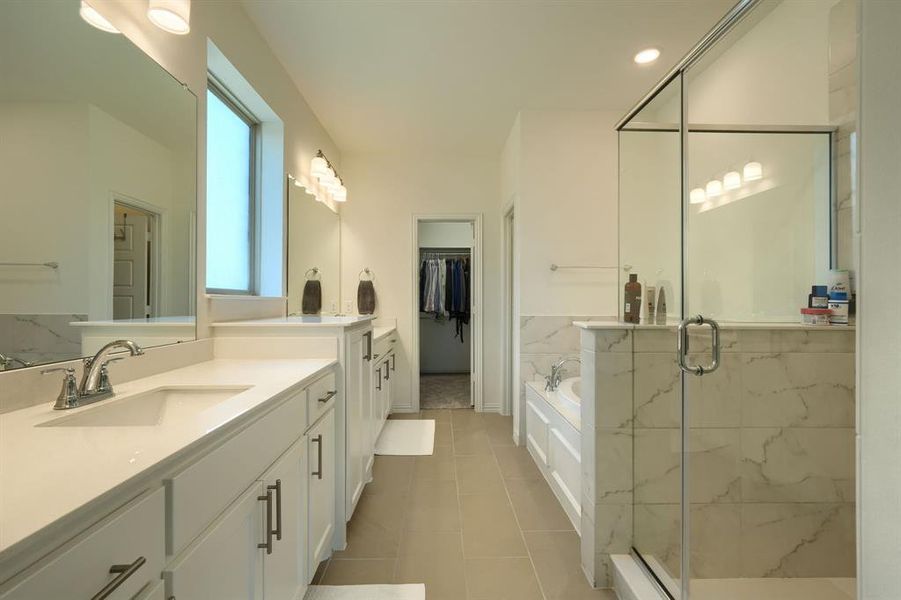 Bathroom featuring tile floors, vanity with extensive cabinet space, and shower with separate bathtub