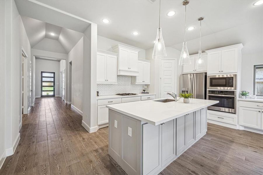 The grand entry features high ceilings and a beautiful modern glass entry door. The wooden-look tile flooring enhances the bright and open space, seamlessly leading to the family living area.
