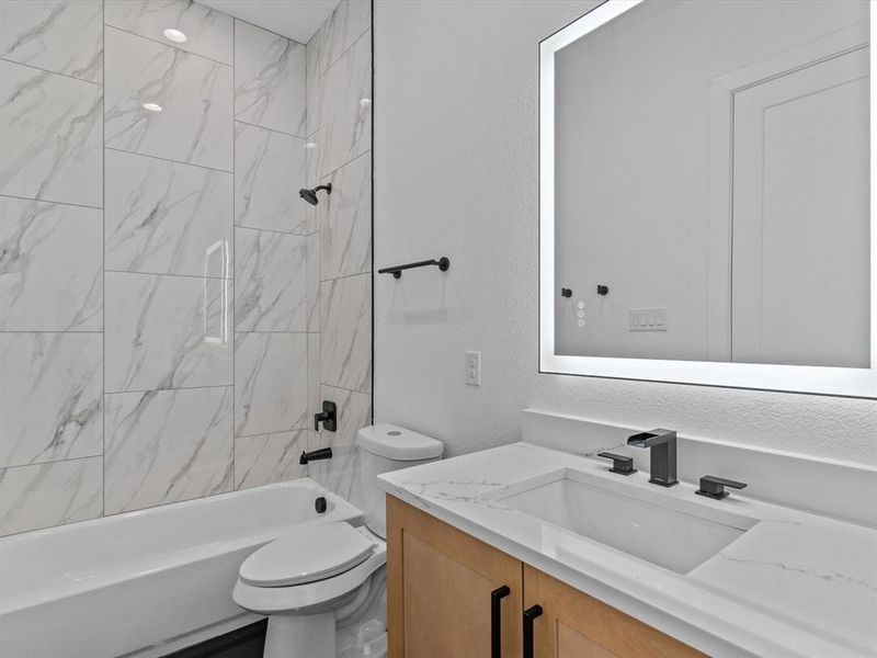 Full bathroom with tiled shower / bath combo, vanity, and toilet