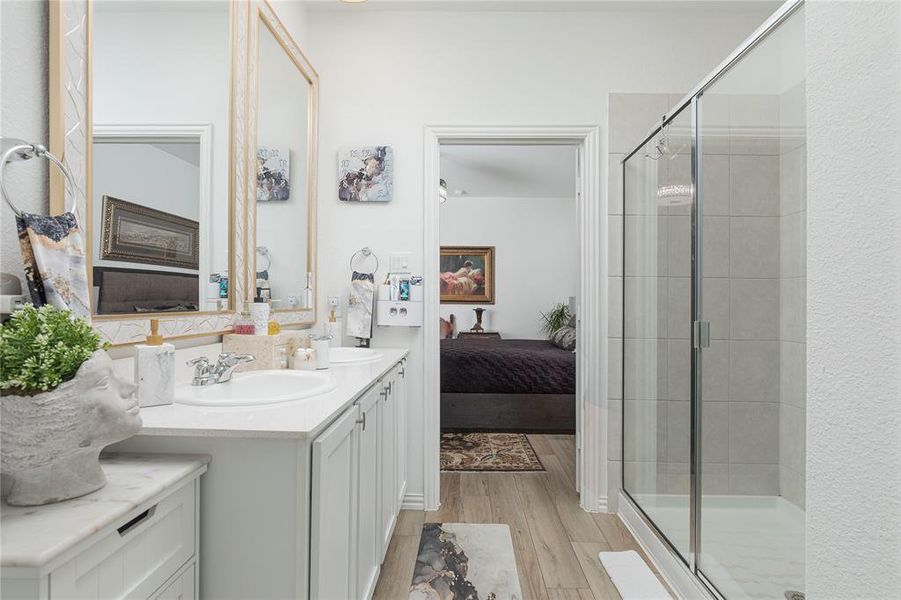 Bathroom with vanity, hardwood / wood-style floors, and a shower with door