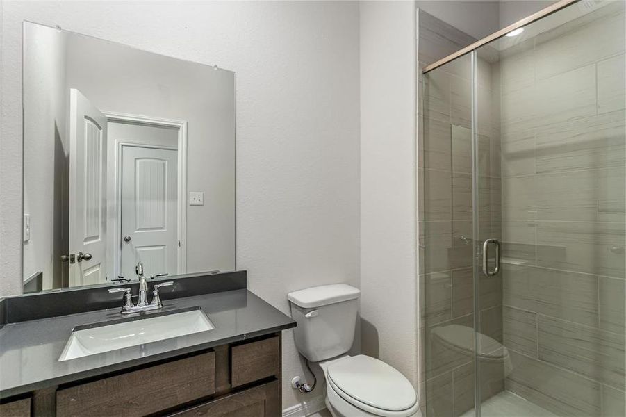 The secondary bathroom includes modern fixtures, a sleek vanity, and a glass-enclosed shower, ensuring comfort and convenience for guests and family alike. Photos are from another Rylan floor plan.