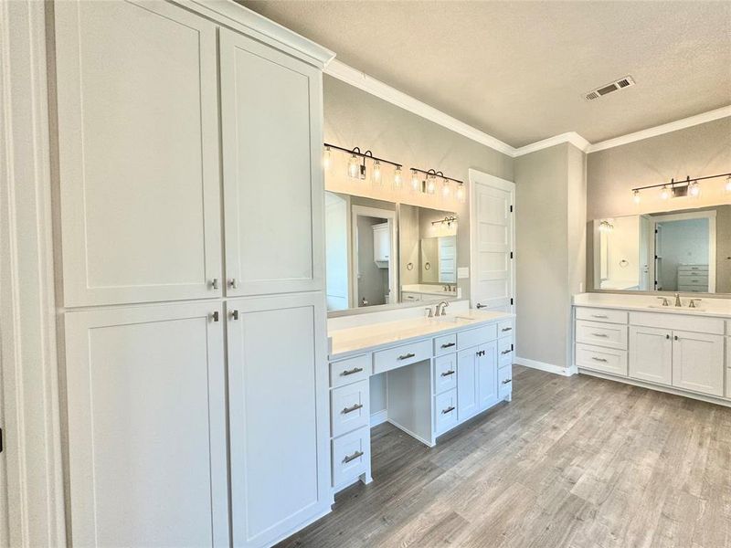 Primary Bathroom with a textured ceiling, vanity, ornamental molding, and hardwood / wood-style floors