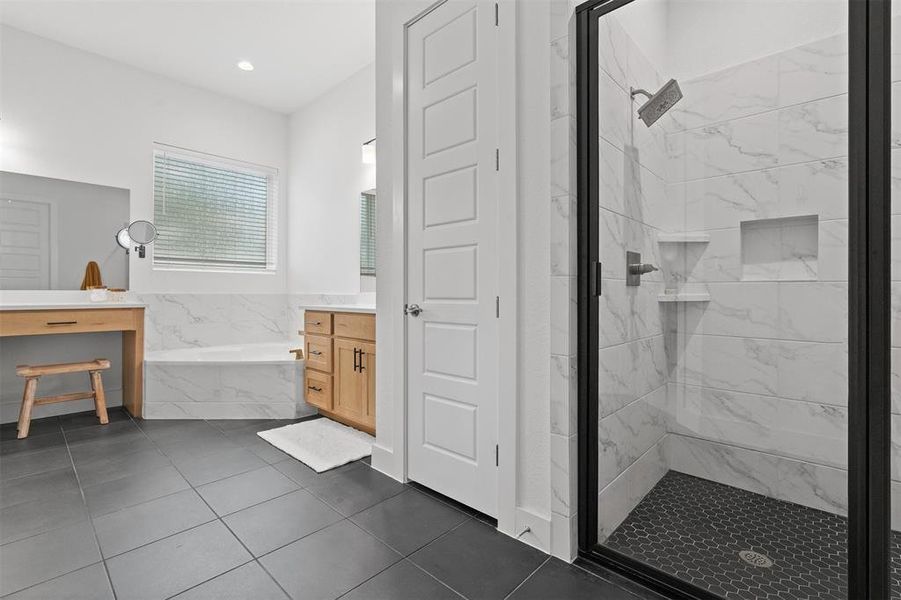 separate vanities, a soaking tub, and a walk-in shower with a rainfall shower head