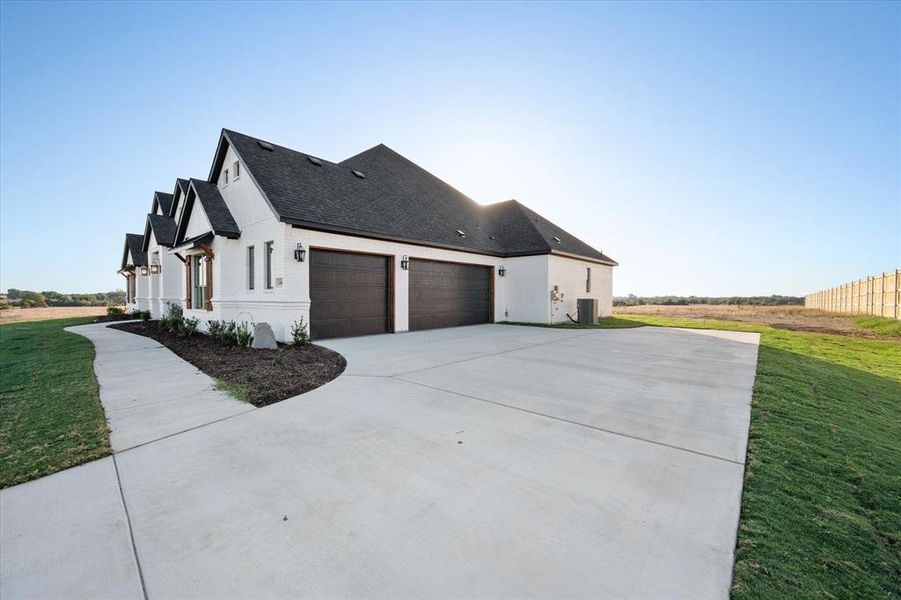 View of side of property with central air condition unit, a garage, and a lawn