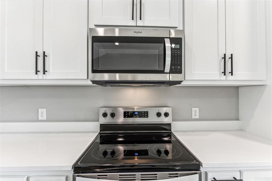 Kitchen featuring appliances with stainless steel finishes and white cabinetry