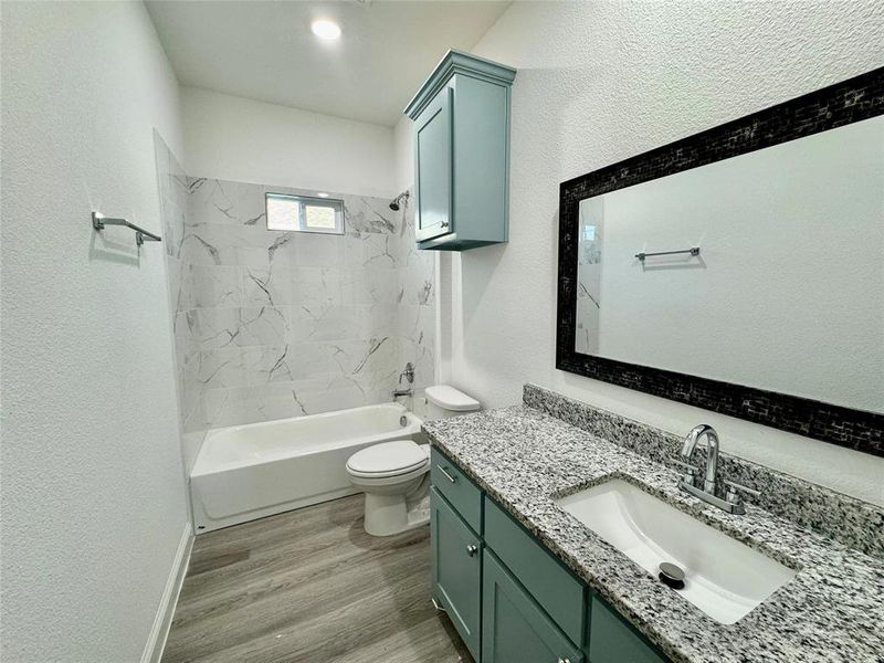 Full bathroom featuring vanity, tiled shower / bath combo, toilet, and hardwood / wood-style flooring