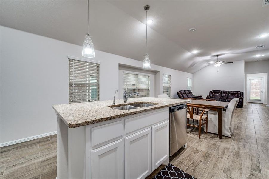 Kitchen with white cabinetry, sink, an island with sink, decorative light fixtures, and dishwasher