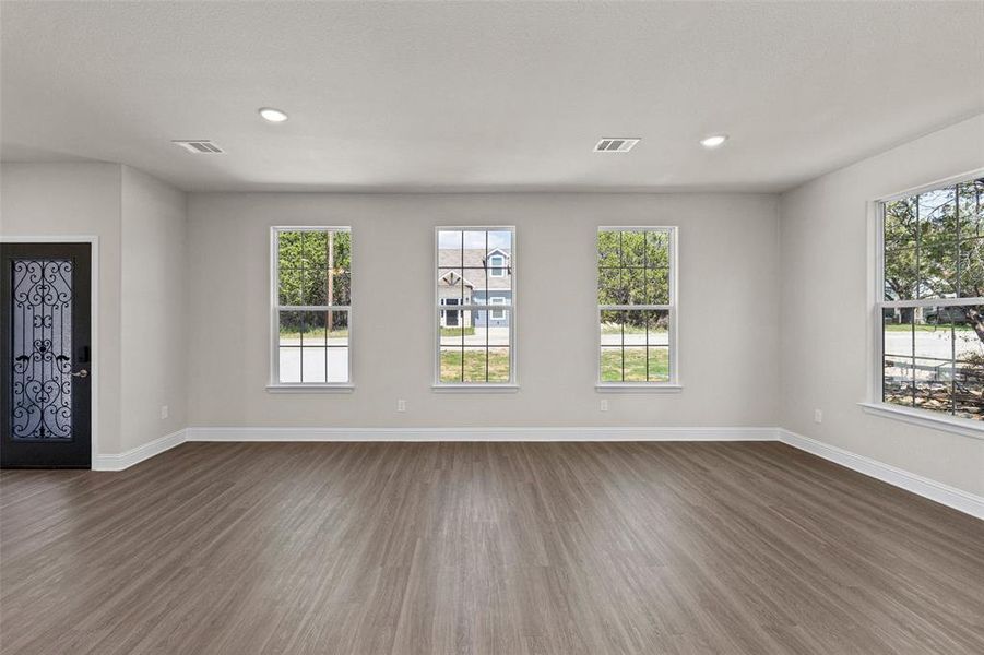 Unfurnished living room with ceiling fan, plenty of natural light, and dark wood-type flooring