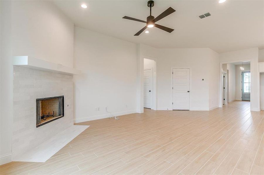 Unfurnished living room featuring ceiling fan, light hardwood / wood-style flooring, and a tile fireplace