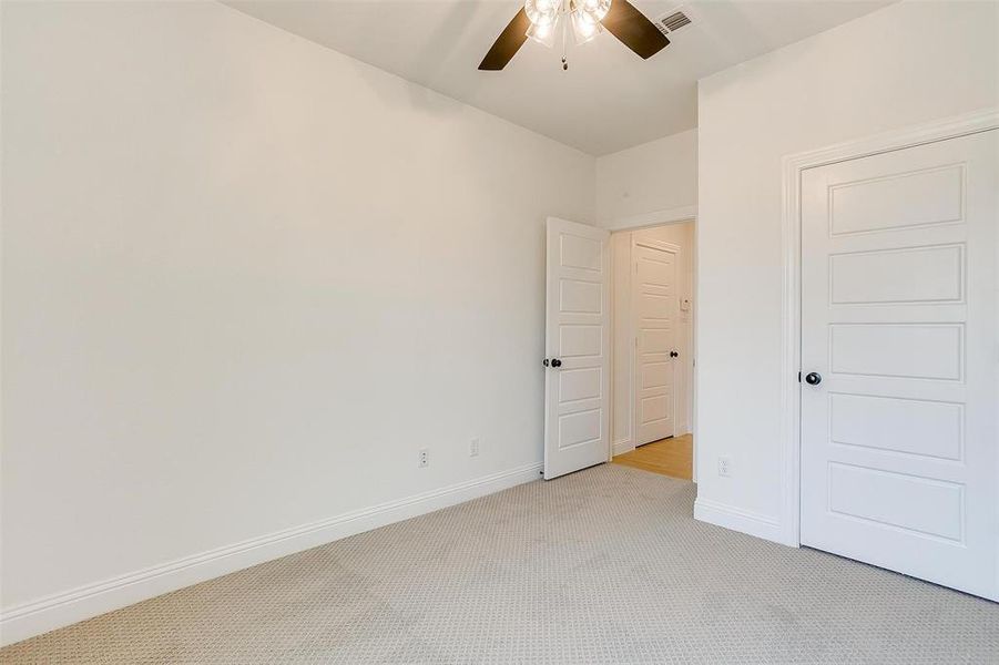 Unfurnished bedroom with ceiling fan and light colored carpet