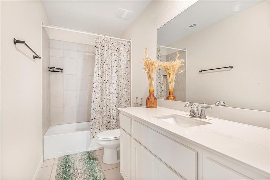 Full bathroom with shower / tub combo, vanity, toilet, and tile patterned floors