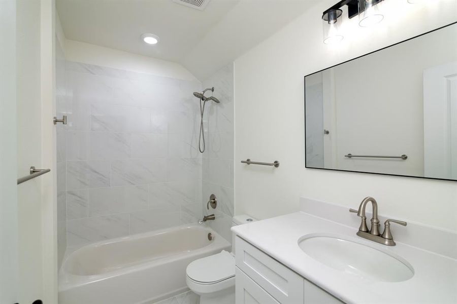 Full bathroom with tiled shower / bath, vanity, and toilet