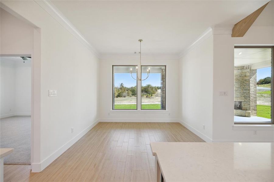 Unfurnished dining area featuring a notable chandelier, light hardwood / wood-style floors, and crown molding