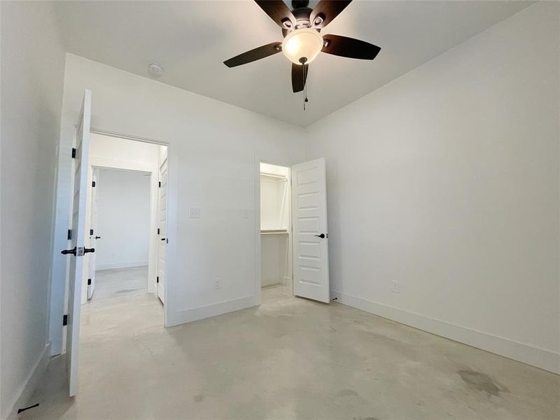 Unfurnished bedroom with ceiling fan and a walk in closet