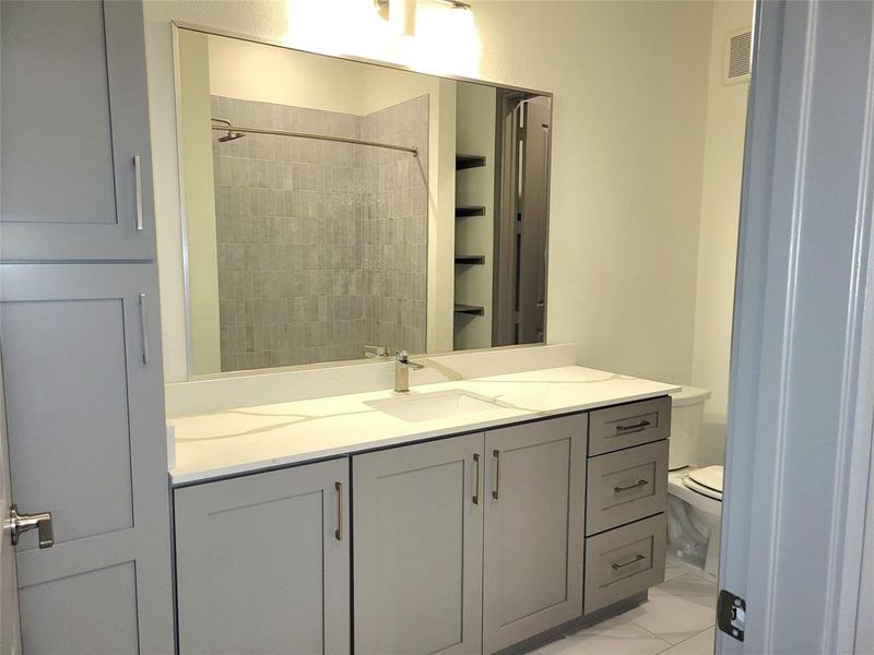 Bathroom with tile flooring, toilet, and vanity with extensive cabinet space