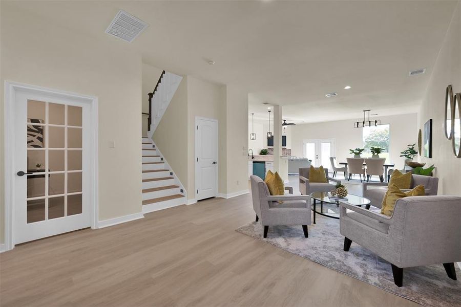 The first floor office can be seen through the glass door to the left. Light colored laminate flooring throughout the space makes it bright and modern.