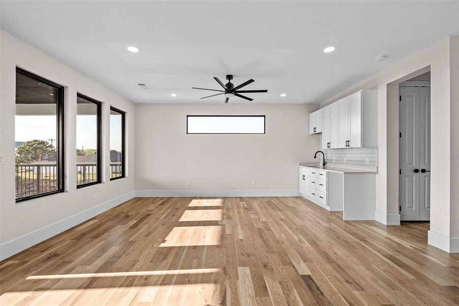 Unfurnished living room featuring ceiling fan, plenty of natural light, sink, and light hardwood / wood-style flooring