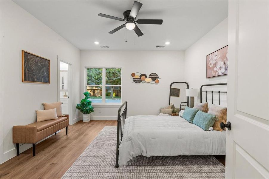 Bedroom with light hardwood / wood-style floors, connected bathroom, and ceiling fan