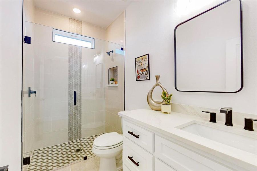 Bathroom with tile patterned flooring, vanity, toilet, and a shower with door